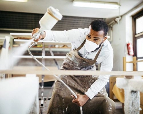 Lackierer bei der Arbeit in einer Farbnebelkabine